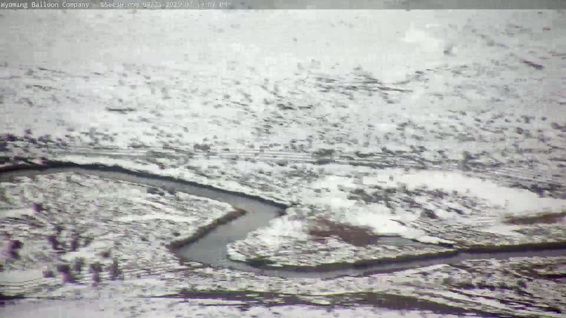 A snow-covered landscape features a meandering river.