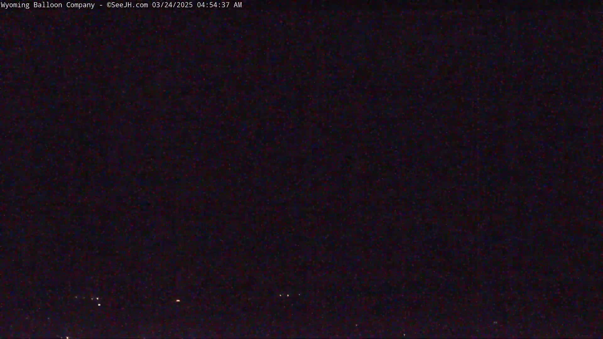 A nighttime, dark sky shows a few faint lights on the horizon.