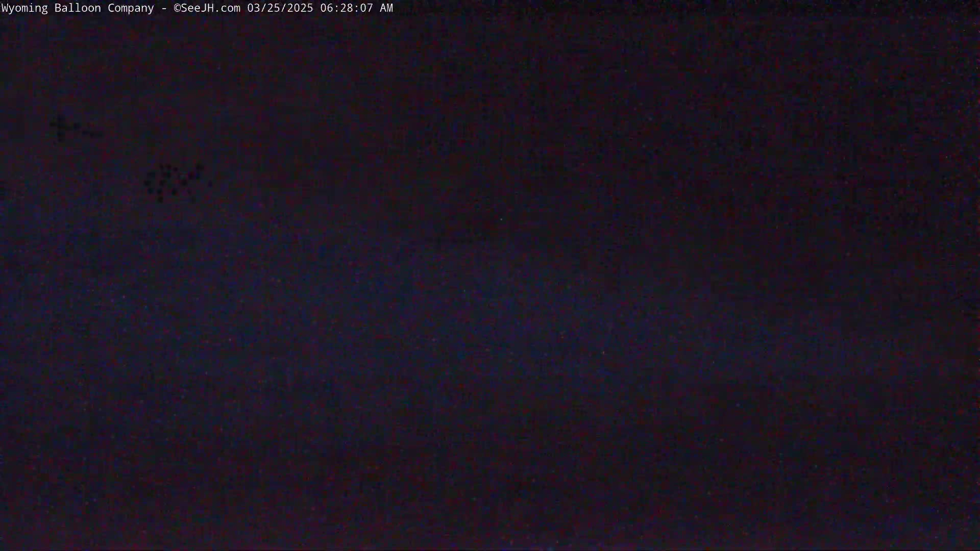 A dark, nighttime scene shows a few small, faint lights in the distance.