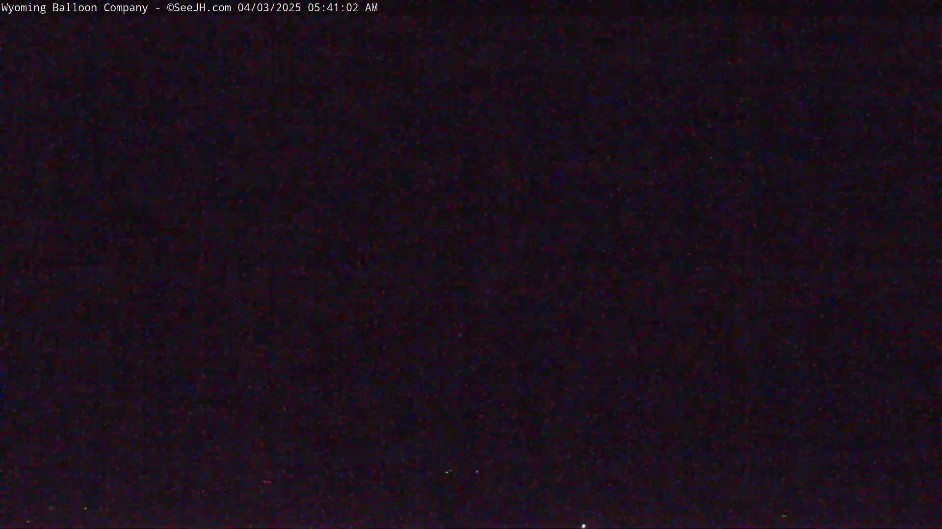A dark, nighttime image shows a mostly black sky with a few faint, distant lights.