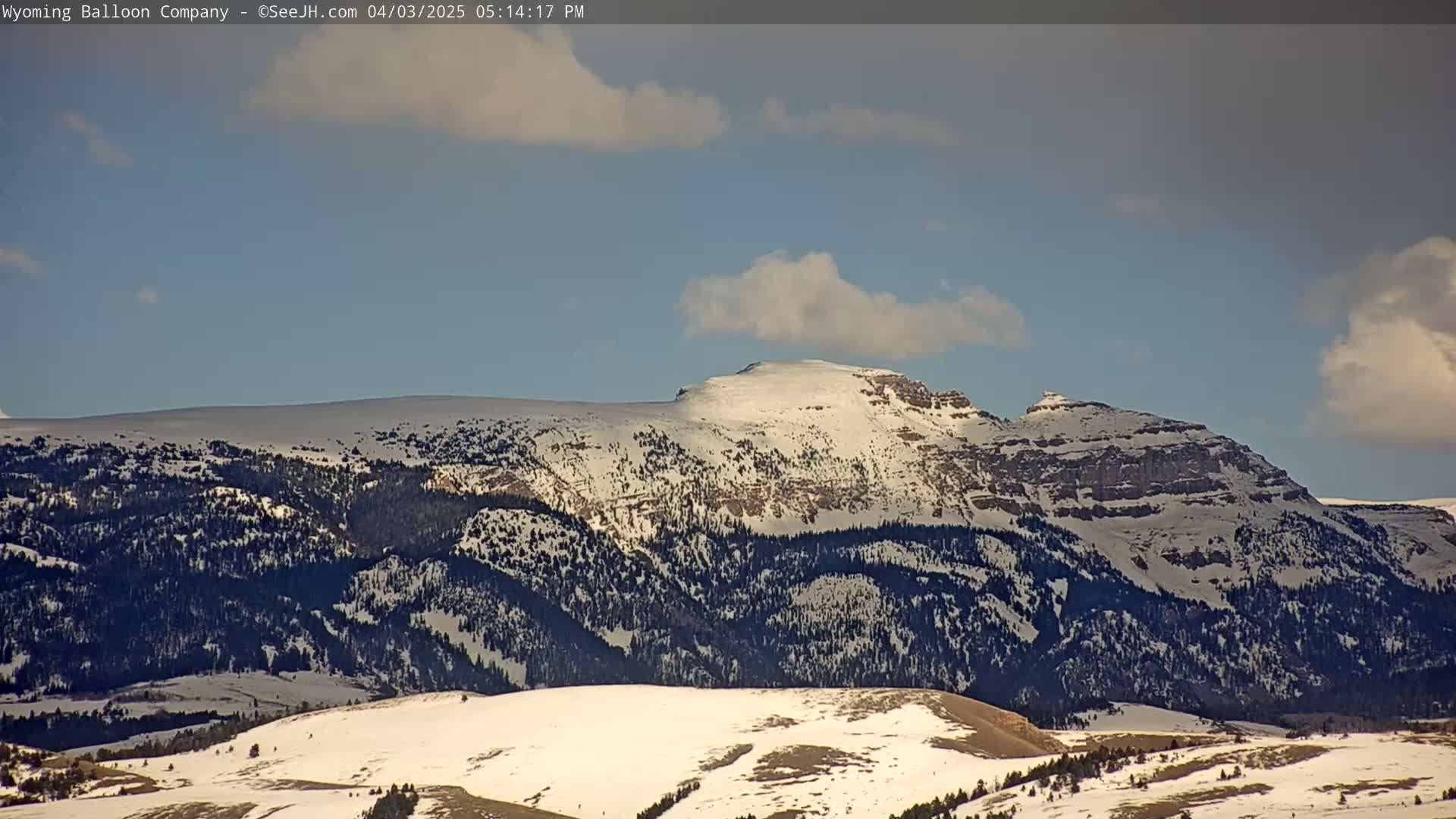 A snow-covered mountain range is visible under a partly cloudy sky.