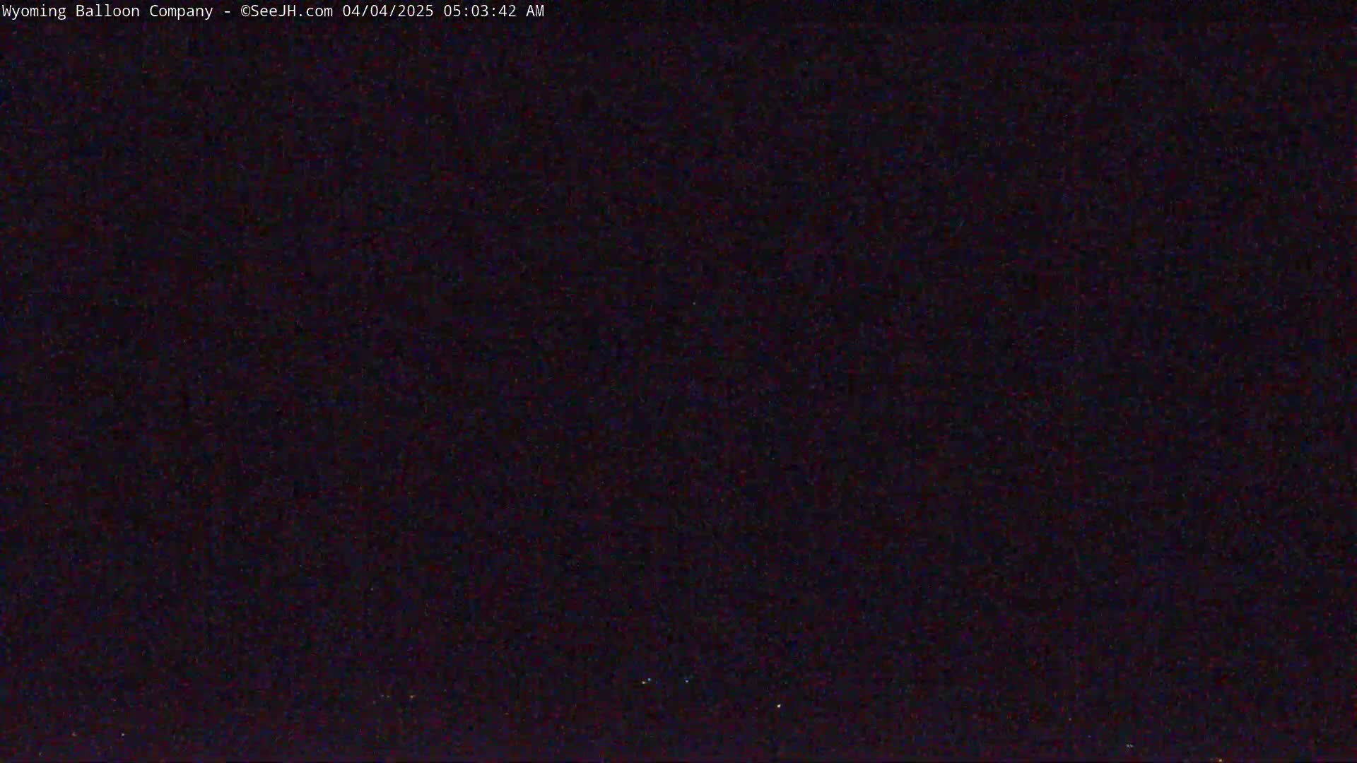 A dark, nighttime scene with a few faint lights visible on the horizon.