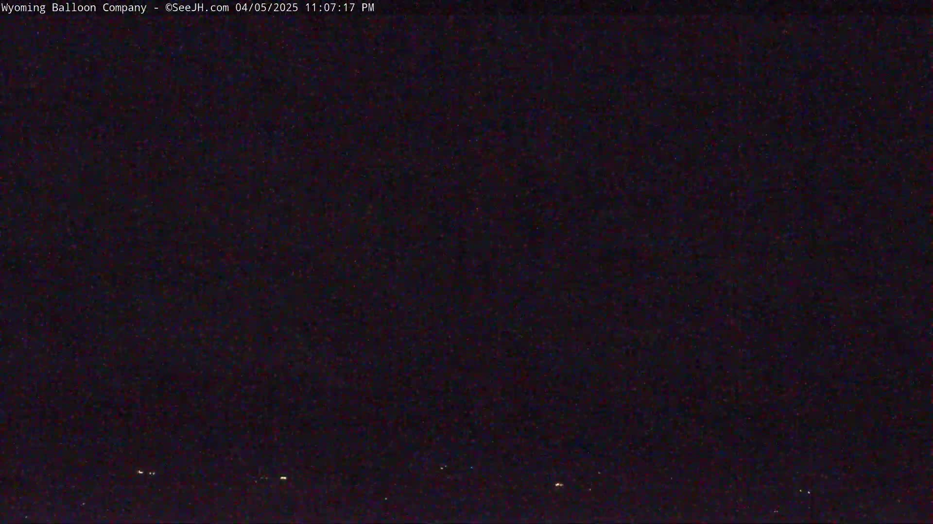 A nighttime, dark sky shows a few faint lights on the horizon.