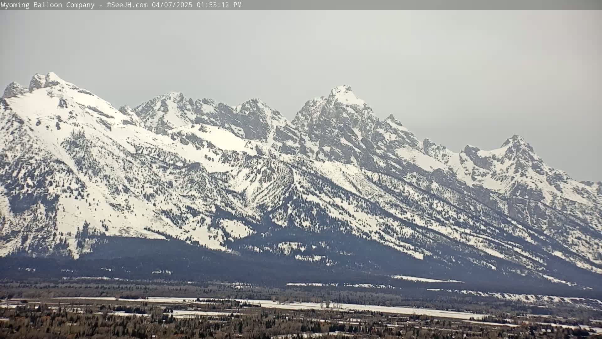 A snow-covered mountain range stretches across the horizon under a hazy sky.