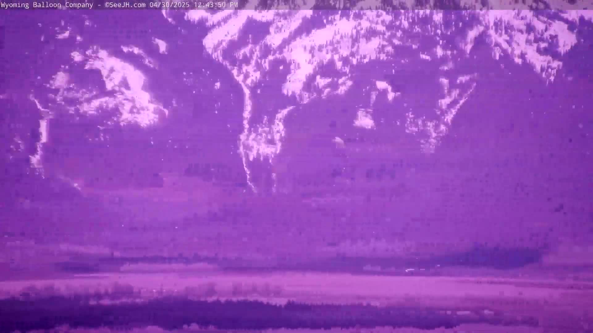 A snow-covered mountain range is visible in the distance, with a flat, purple-tinted land stretching out in the foreground.