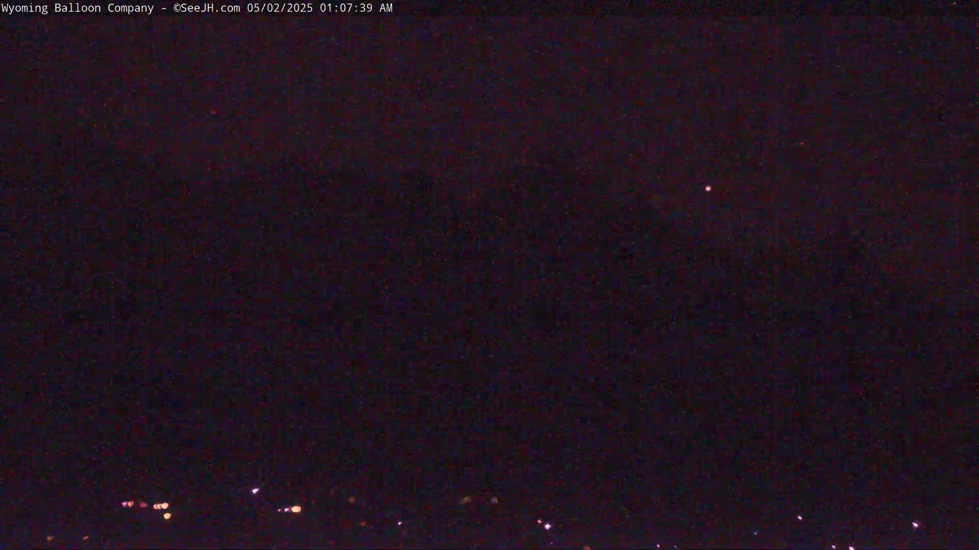 A nighttime, dark sky with a few faint lights visible on the horizon.