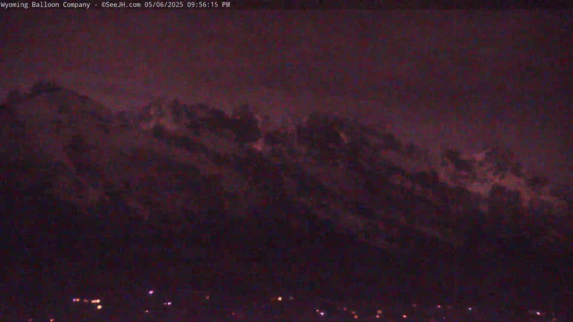 A dark, nighttime view of a mountain range partially obscured by clouds.