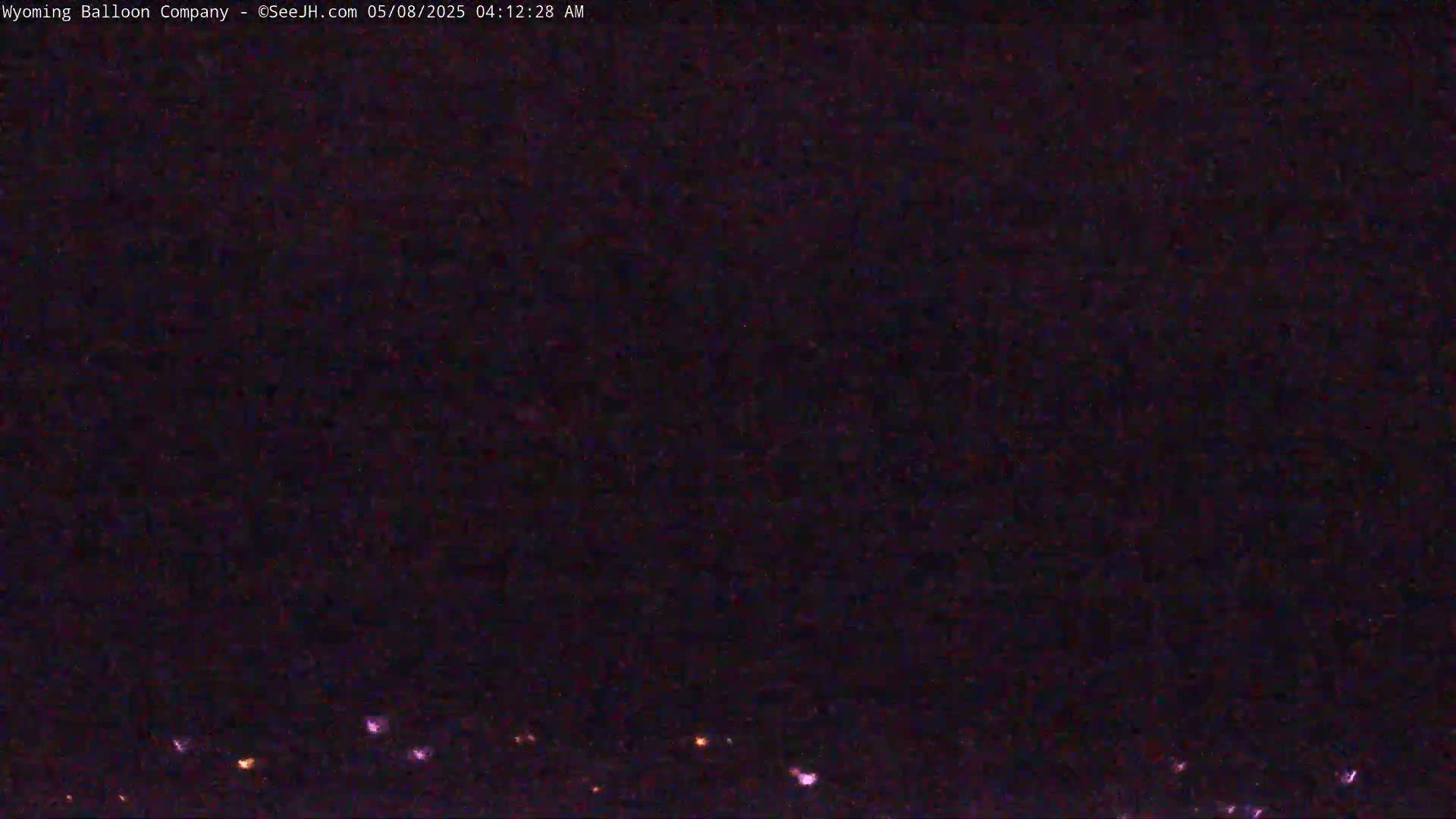 A dark, nighttime scene shows a few small, scattered lights on the horizon.