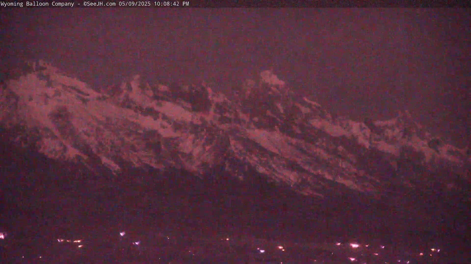 A snow-capped mountain range is visible at dusk or night, with a few scattered lights below.