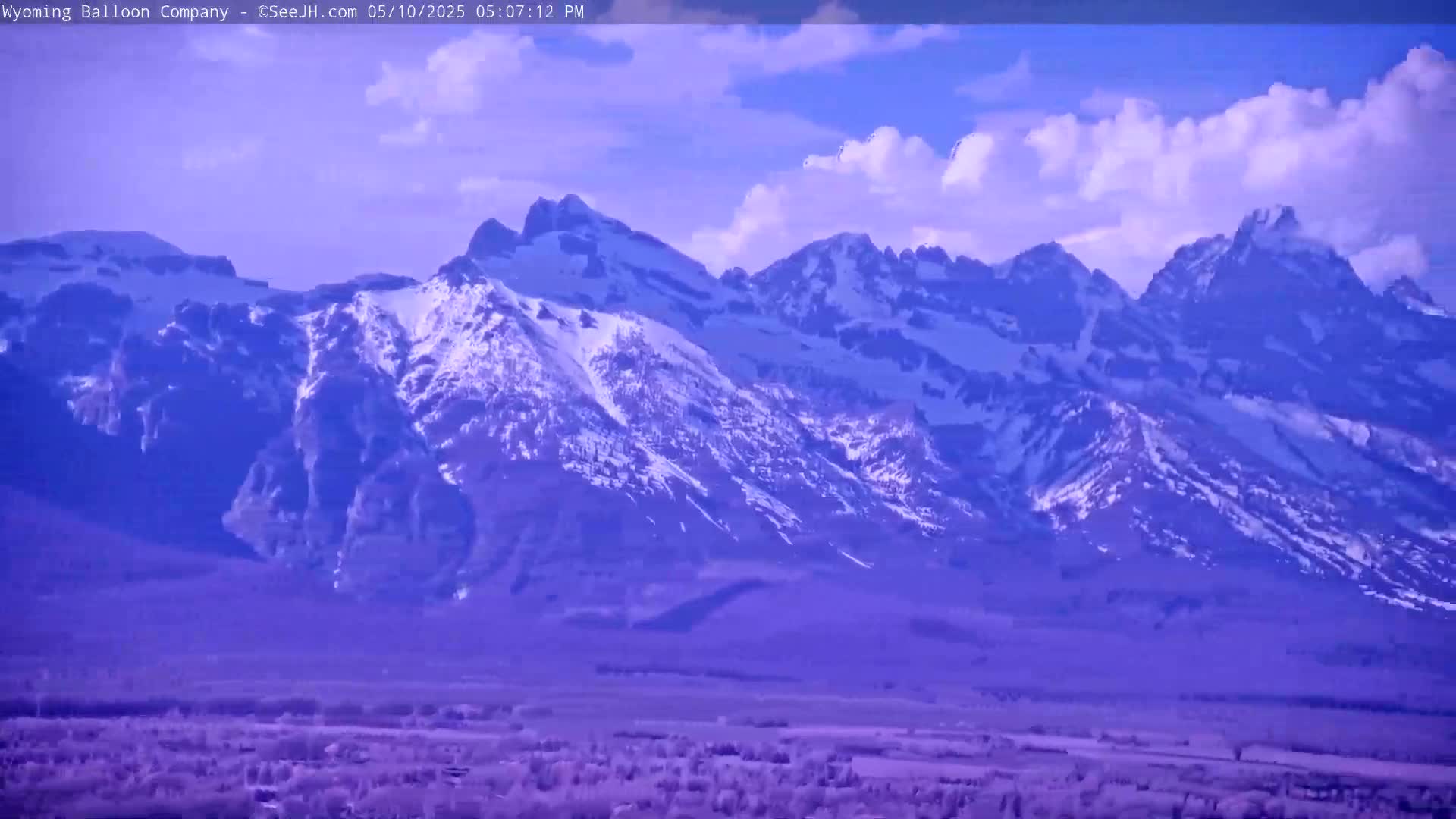 A snow-capped mountain range is visible under a partly cloudy sky.
