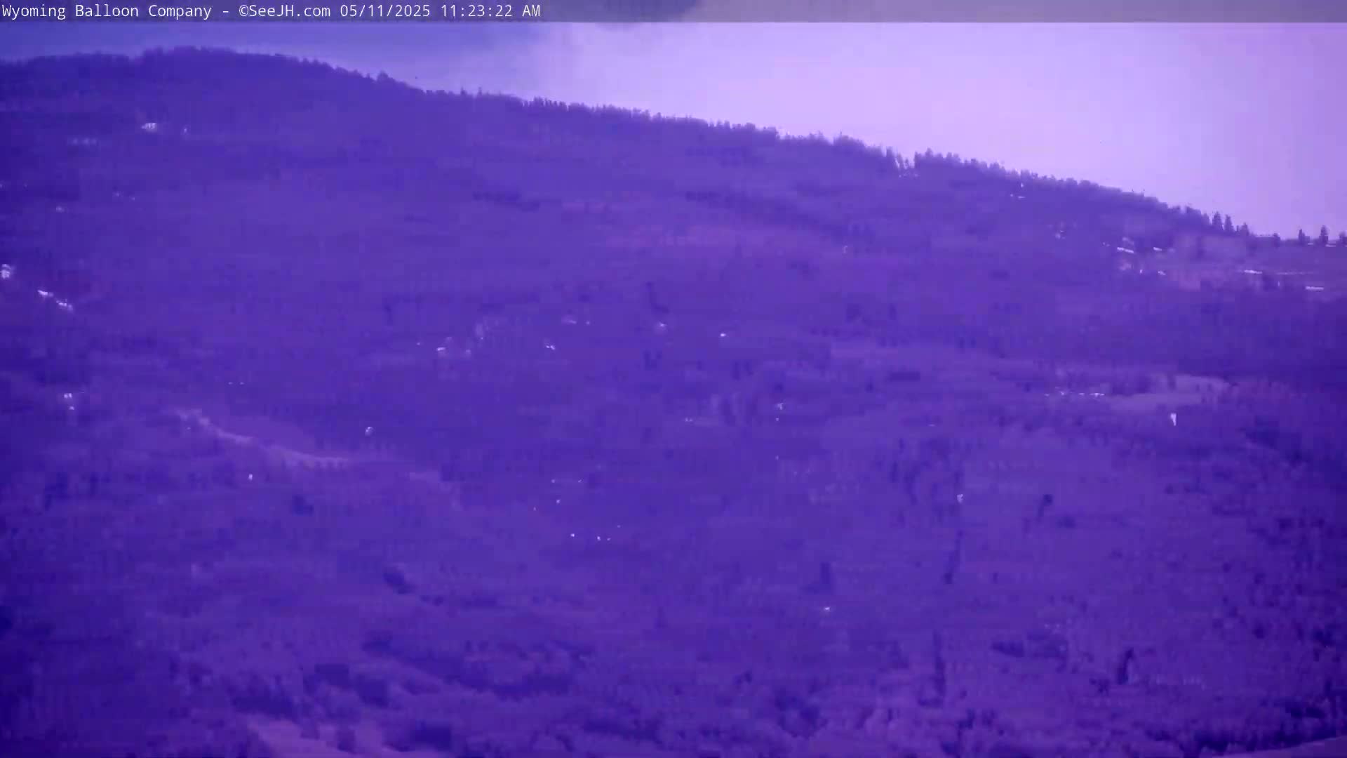 A distant, purple-hued hillside covered in sparse vegetation is visible under a hazy sky.