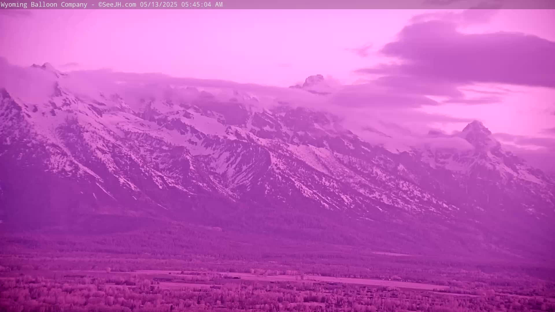 A snow-capped mountain range is visible under a purple-hued sky at dawn.