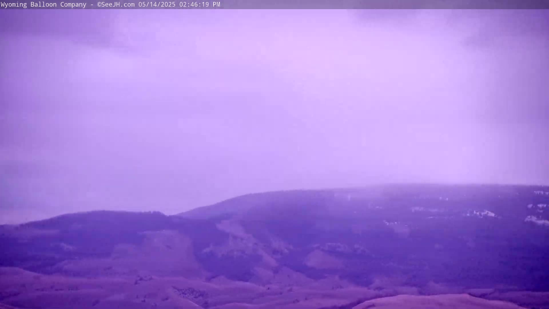 A hazy purple landscape shows rolling hills under an overcast sky.