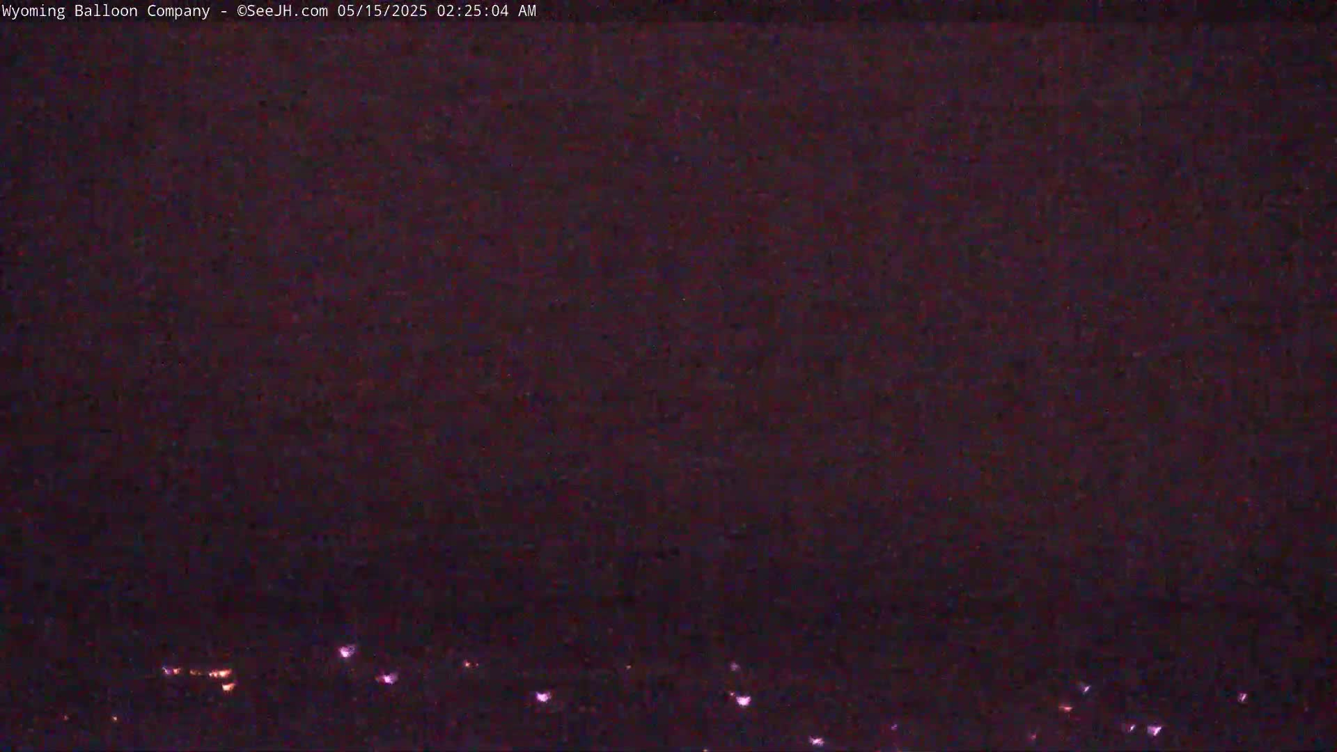 A dark night sky shows a faint line of distant lights on the horizon.