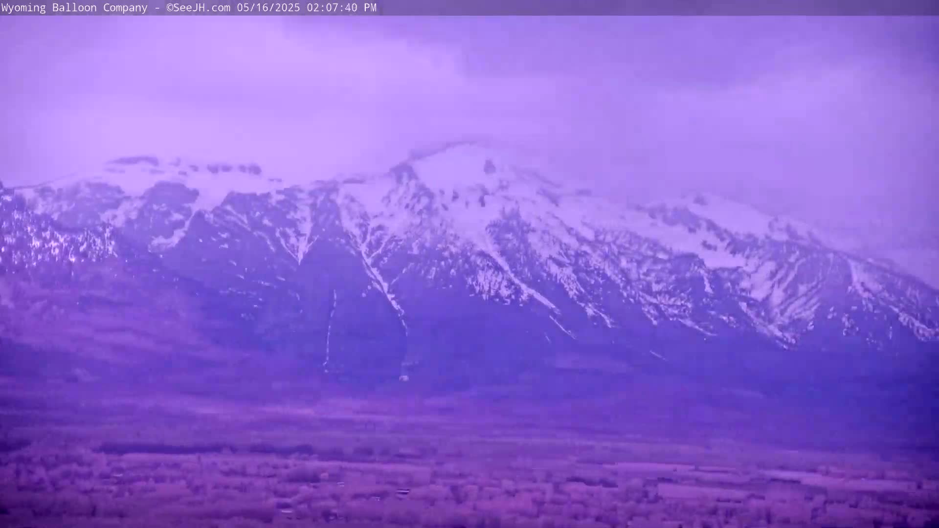 A snow-capped mountain range is visible in the distance under a hazy, purple-hued sky.