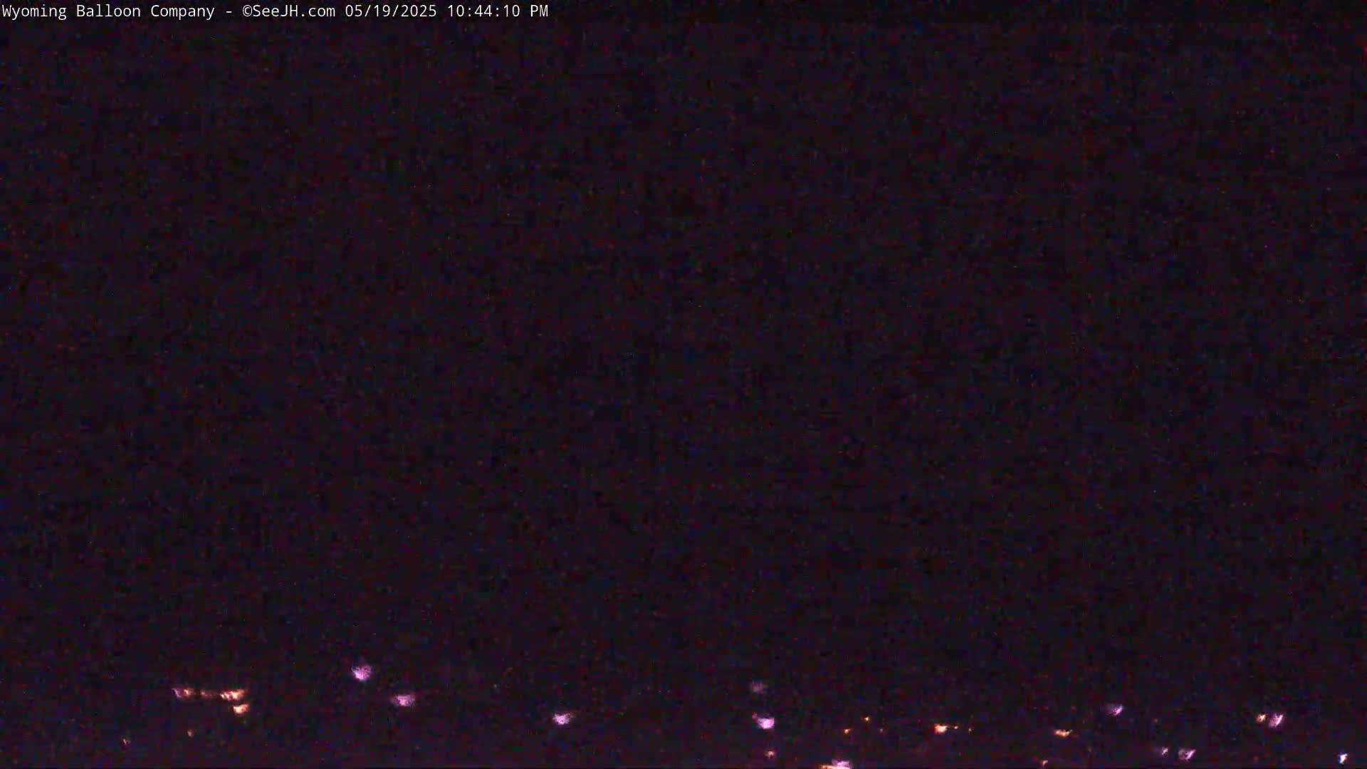 A nighttime, dark view shows a few faint, distant lights along the horizon.