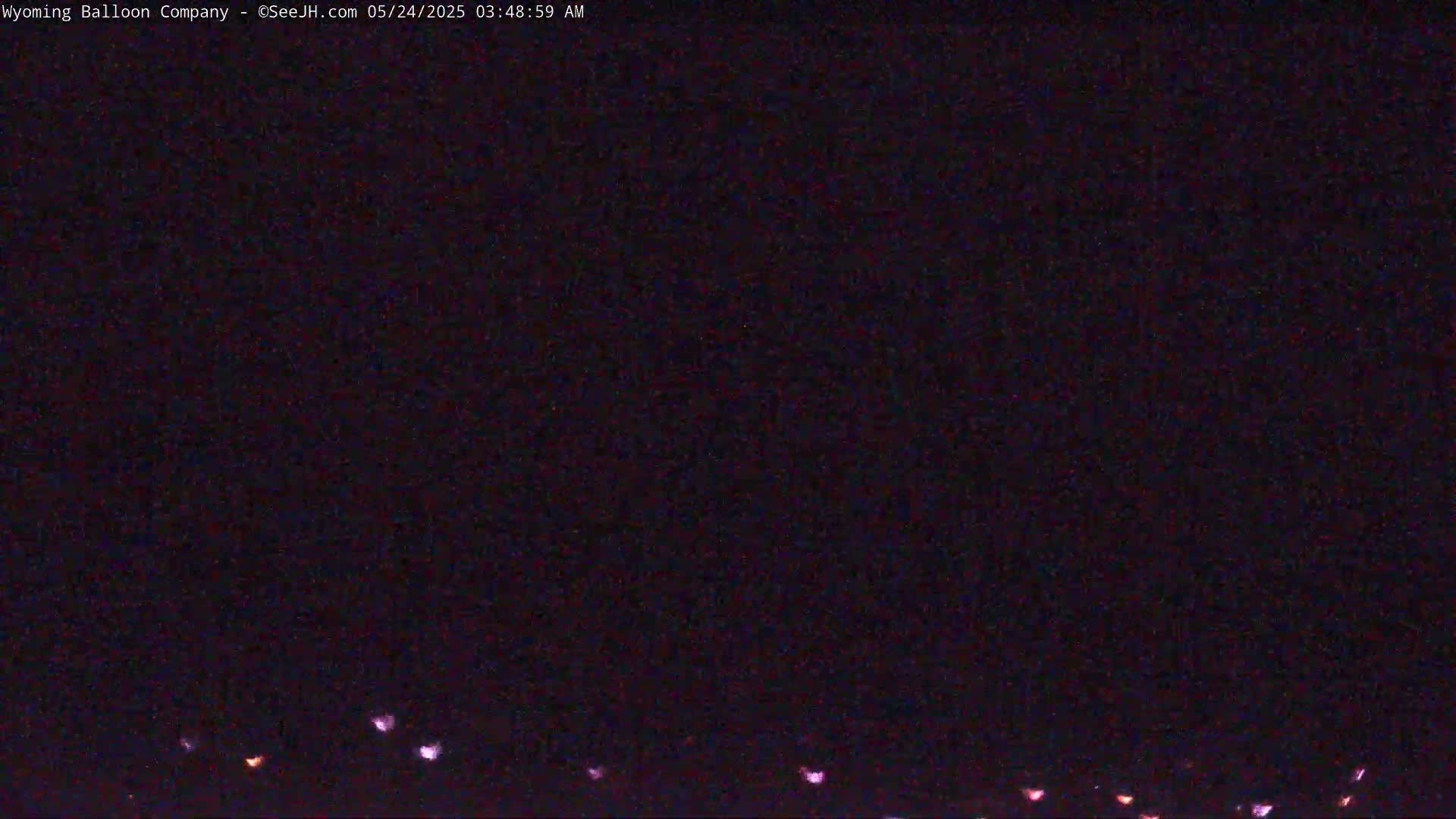 A dark, nighttime scene shows a low line of faint, pinkish lights at the bottom edge.