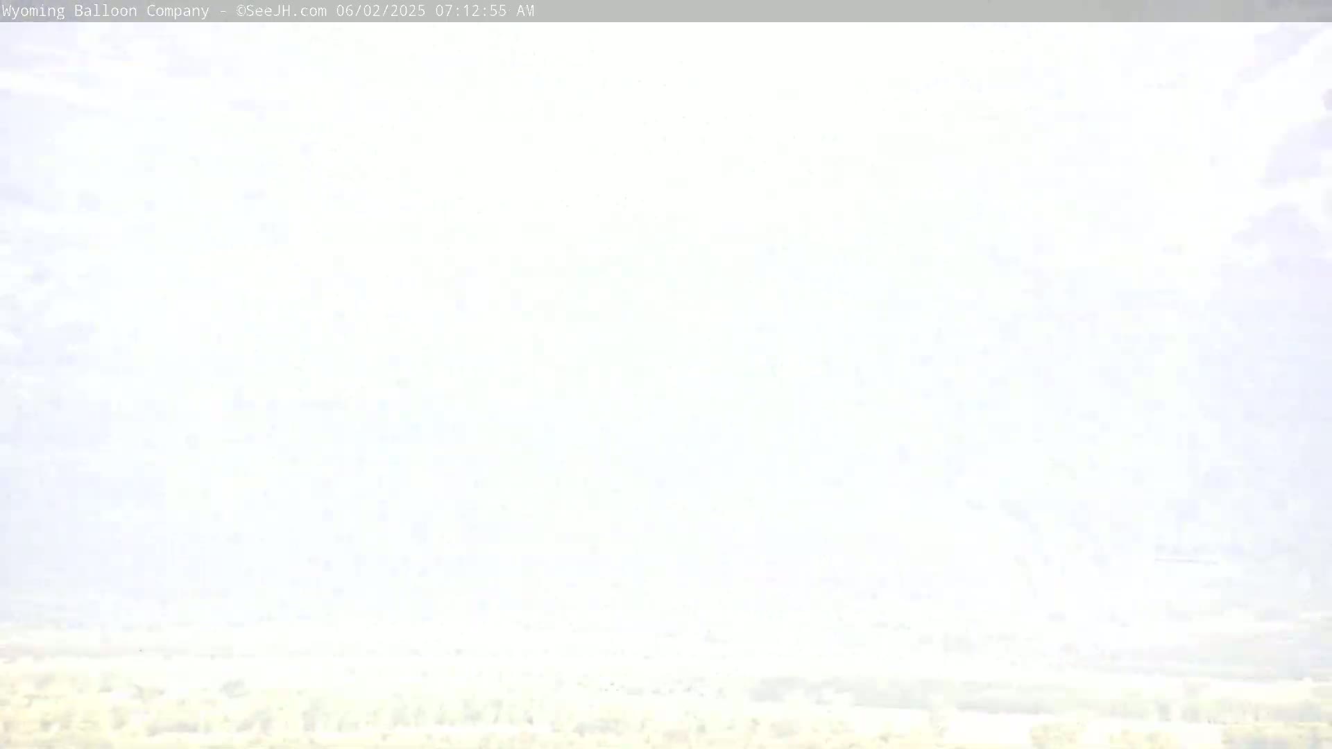 A hazy, light-colored landscape stretches to the horizon under a mostly clear sky.