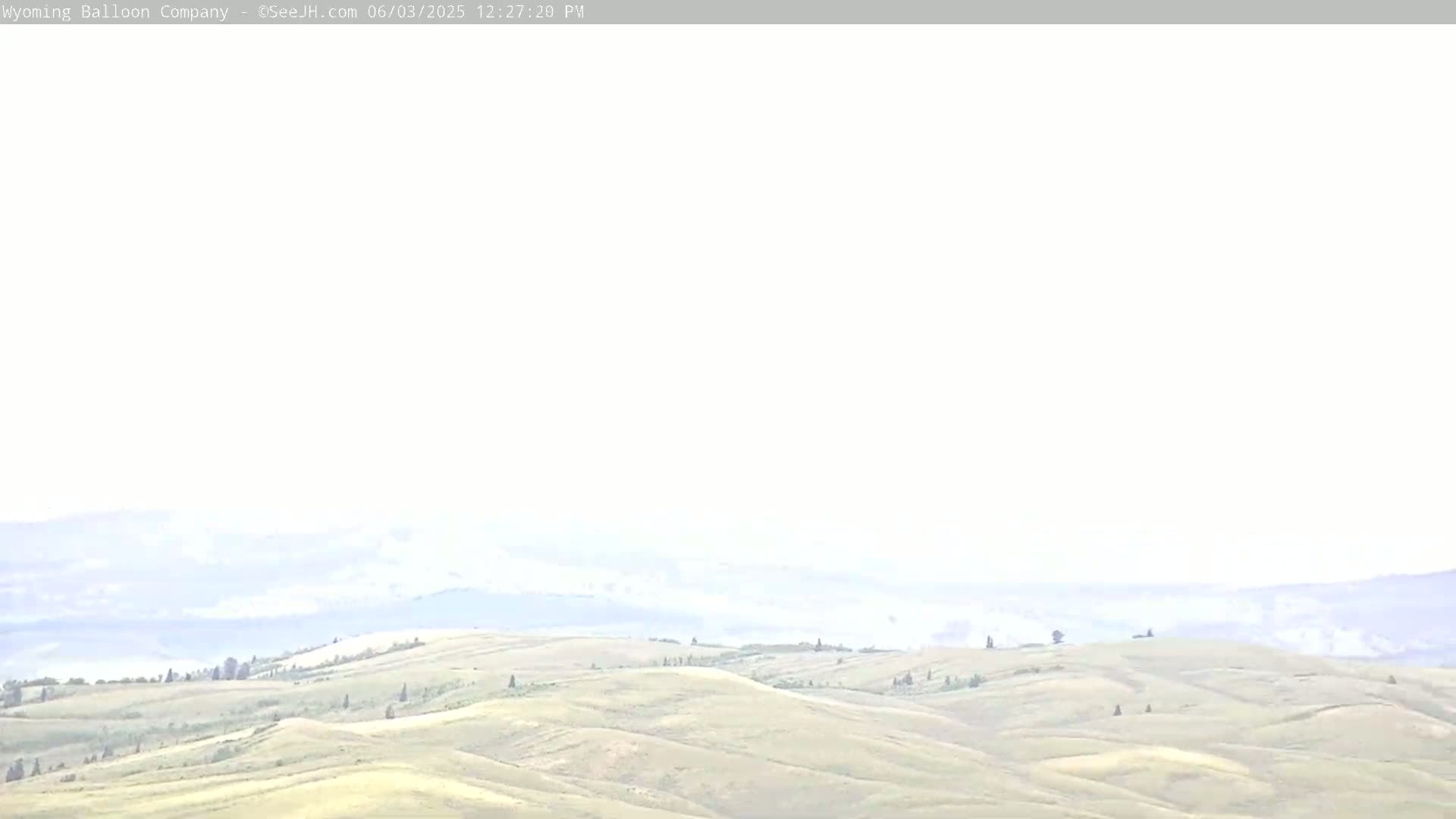 A hazy, light-colored landscape of rolling hills stretches to a distant, misty mountain range.