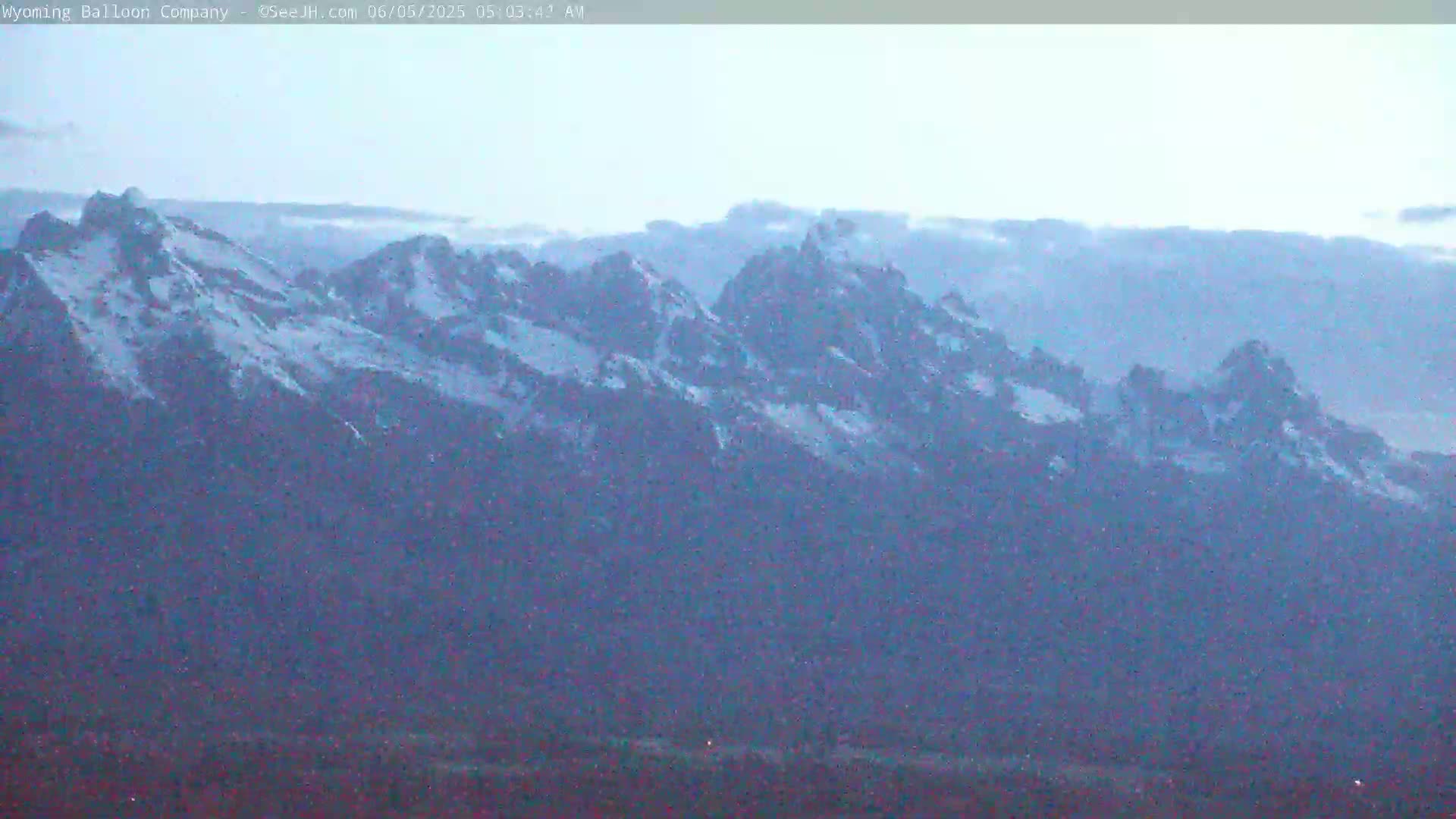 A snow-capped mountain range is visible under a hazy, light-blue sky.