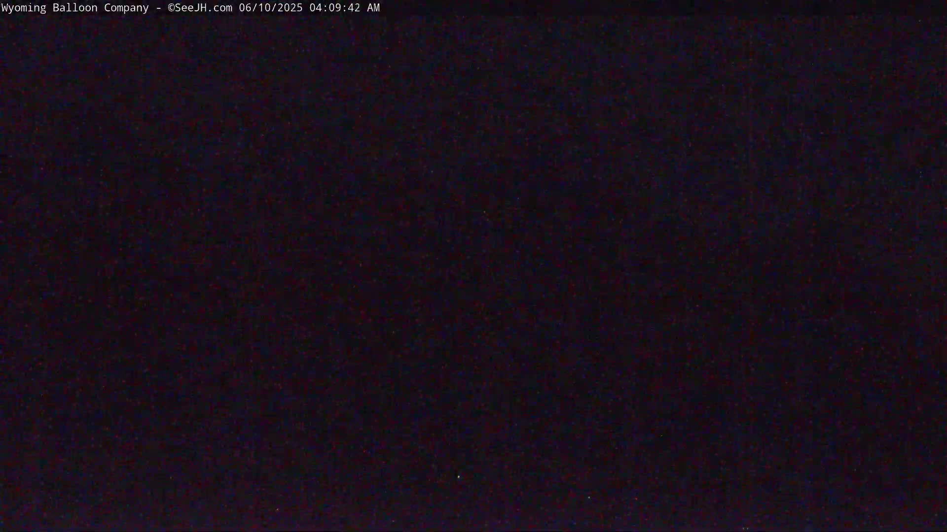 The image shows a dark, nighttime sky with a few faint specks of light.
