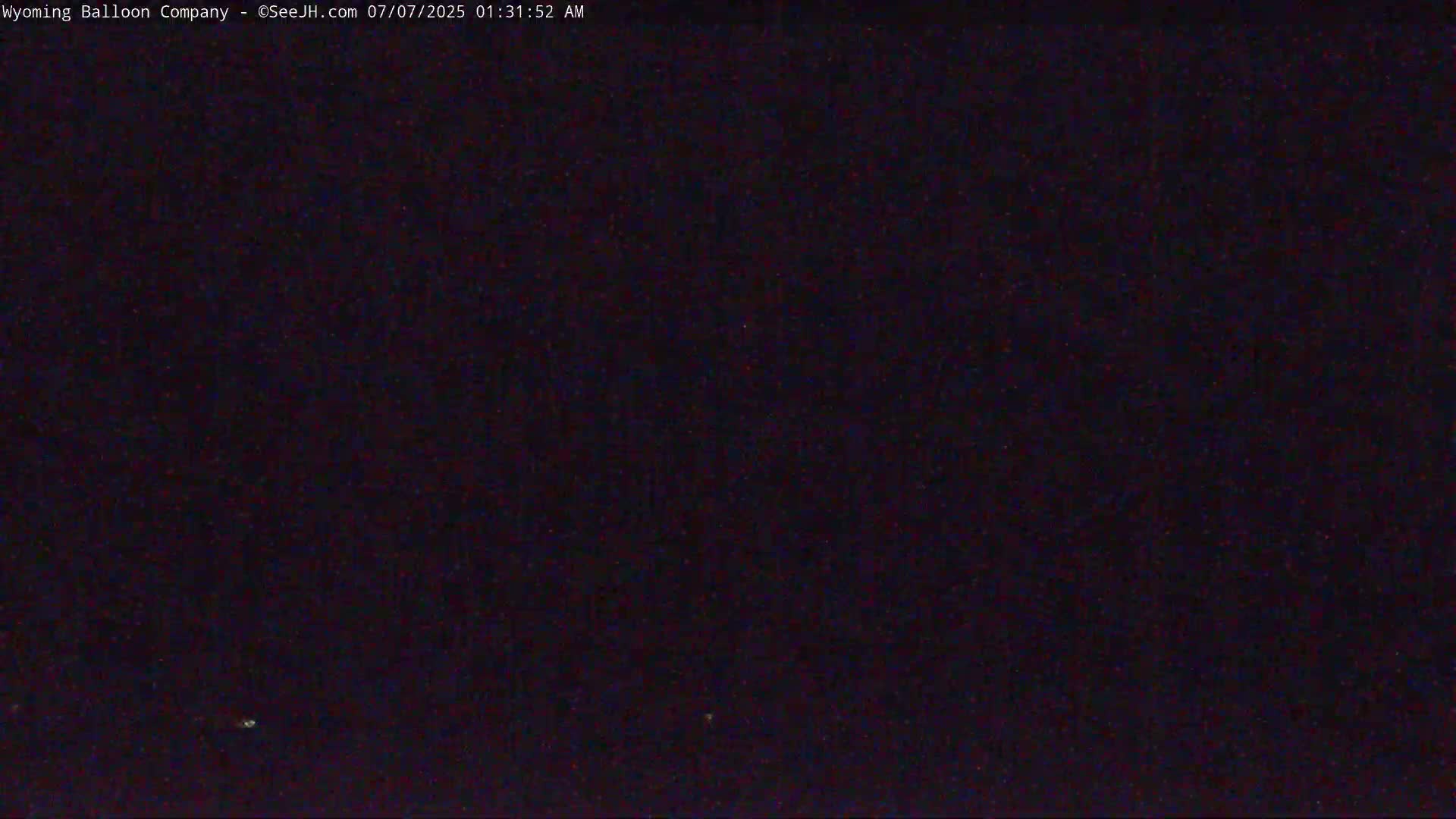 A dark, nighttime image shows a mostly black sky with a few faint, distant lights.