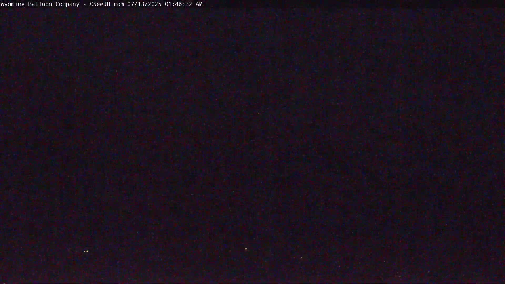 A nighttime image shows a dark sky with a few faint lights visible in the distance.