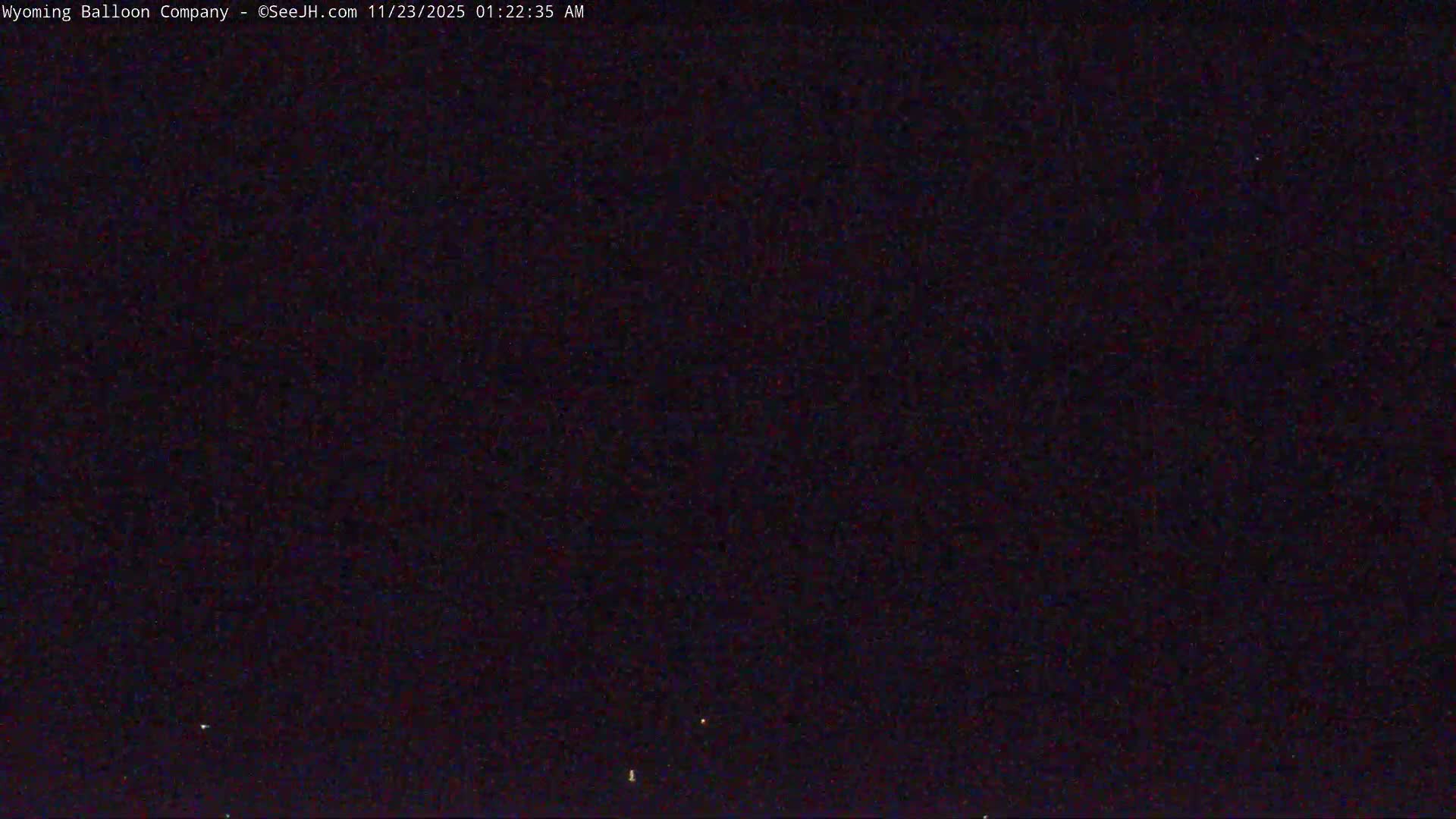 A very dark outdoor scene at night shows only a few faint, scattered specks of light visible against the black sky, suggesting clear weather.