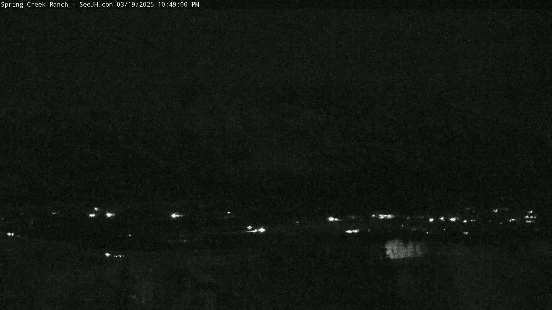 A nighttime view shows a distant line of faint lights against a dark, clear sky.