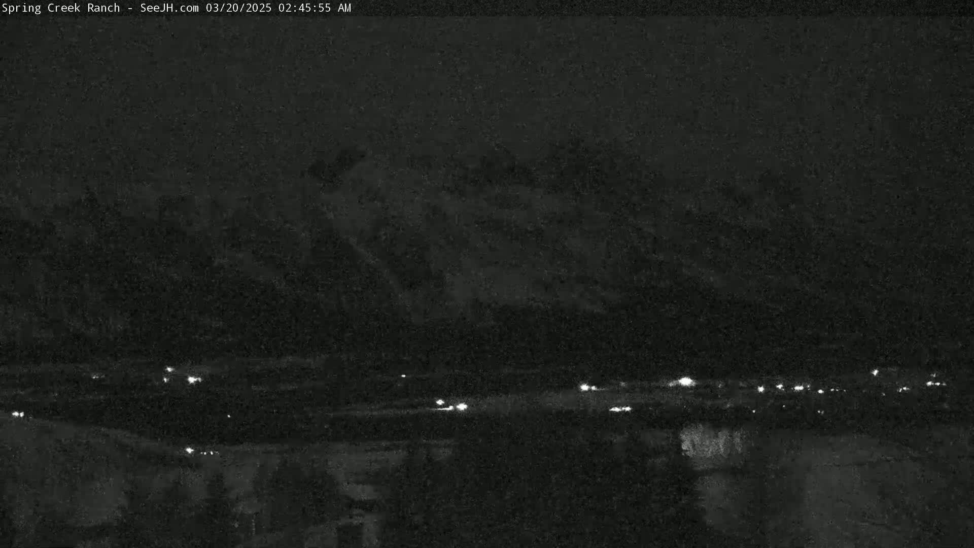 A nighttime long shot shows a dark, mountainous landscape with a few scattered lights visible in the valley below.
