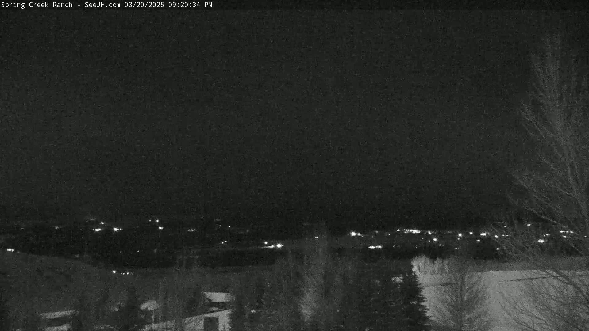 A nighttime long shot shows a distant town's lights under a dark, clear sky.