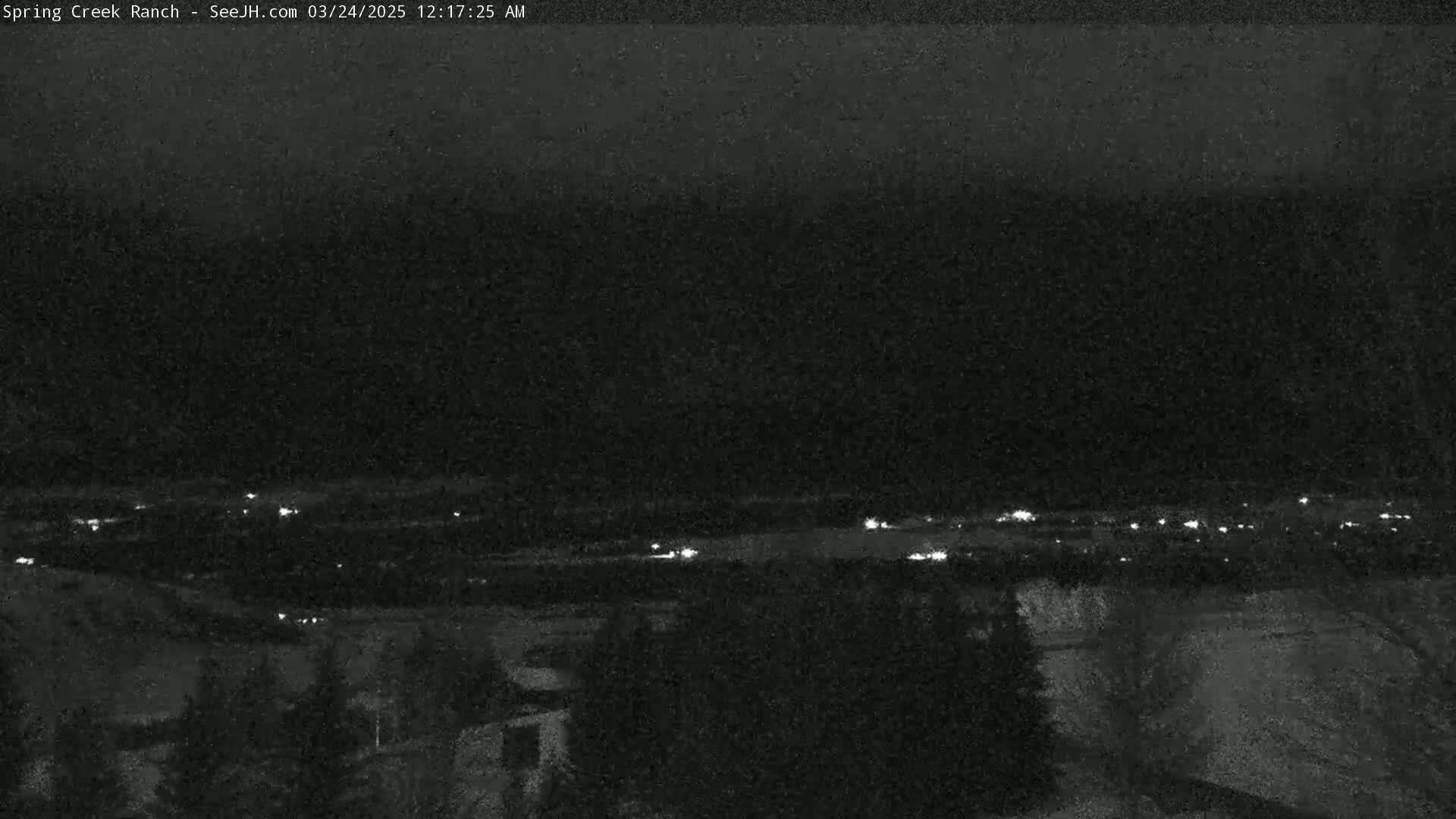 A nighttime, low-light view shows a distant line of lights across a dark landscape.