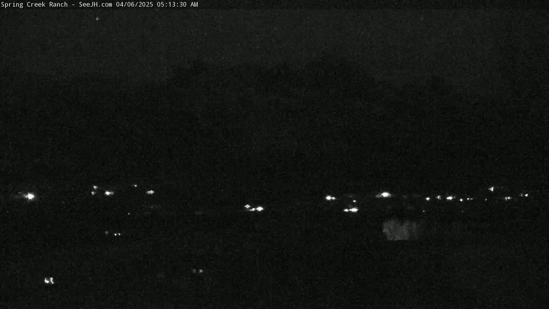 A nighttime, low-light image shows a distant line of lights against a dark sky.