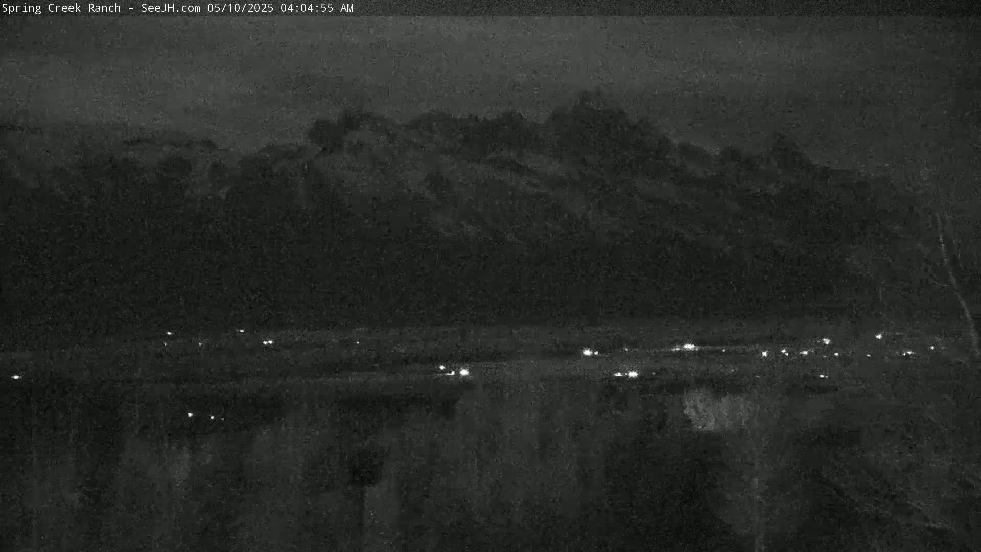 A nighttime long shot shows a dark, mountainous landscape with a line of small, distant lights below, possibly indicating a road.