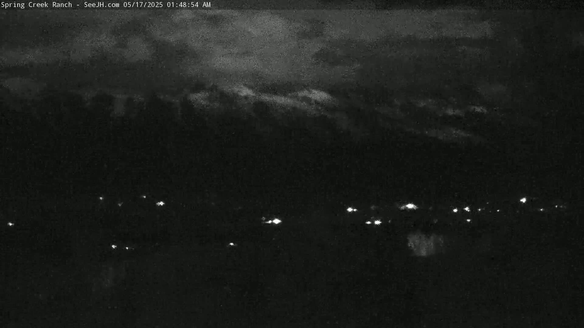 A nighttime, overcast view shows a line of distant lights below a dark sky.
