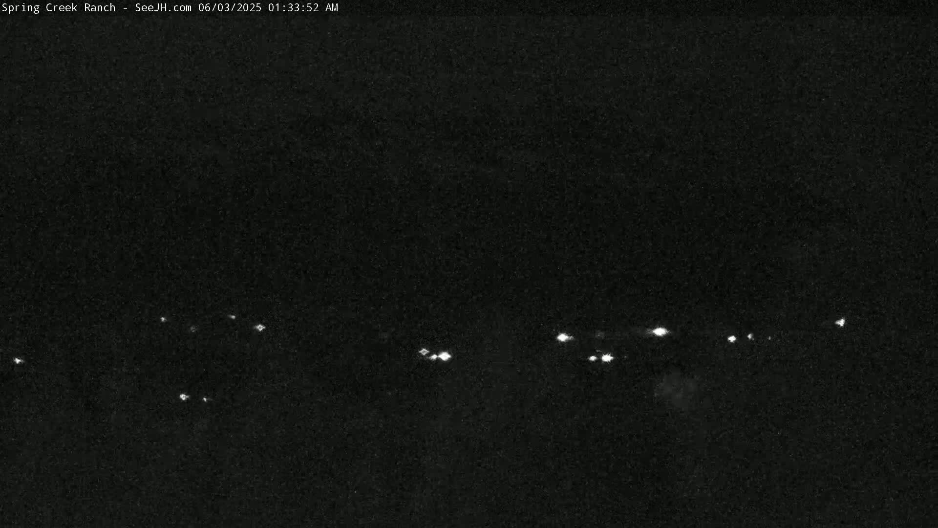 A nighttime view shows a few small, distant lights on a dark horizon.