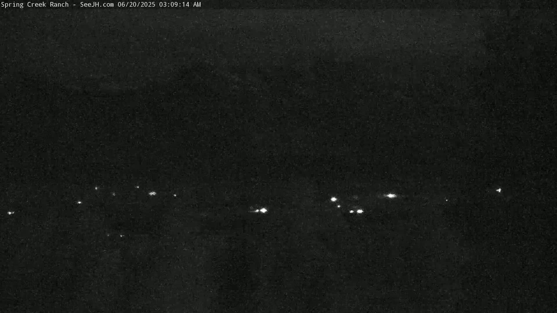 A nighttime, low-light image shows a line of distant lights on a dark horizon.