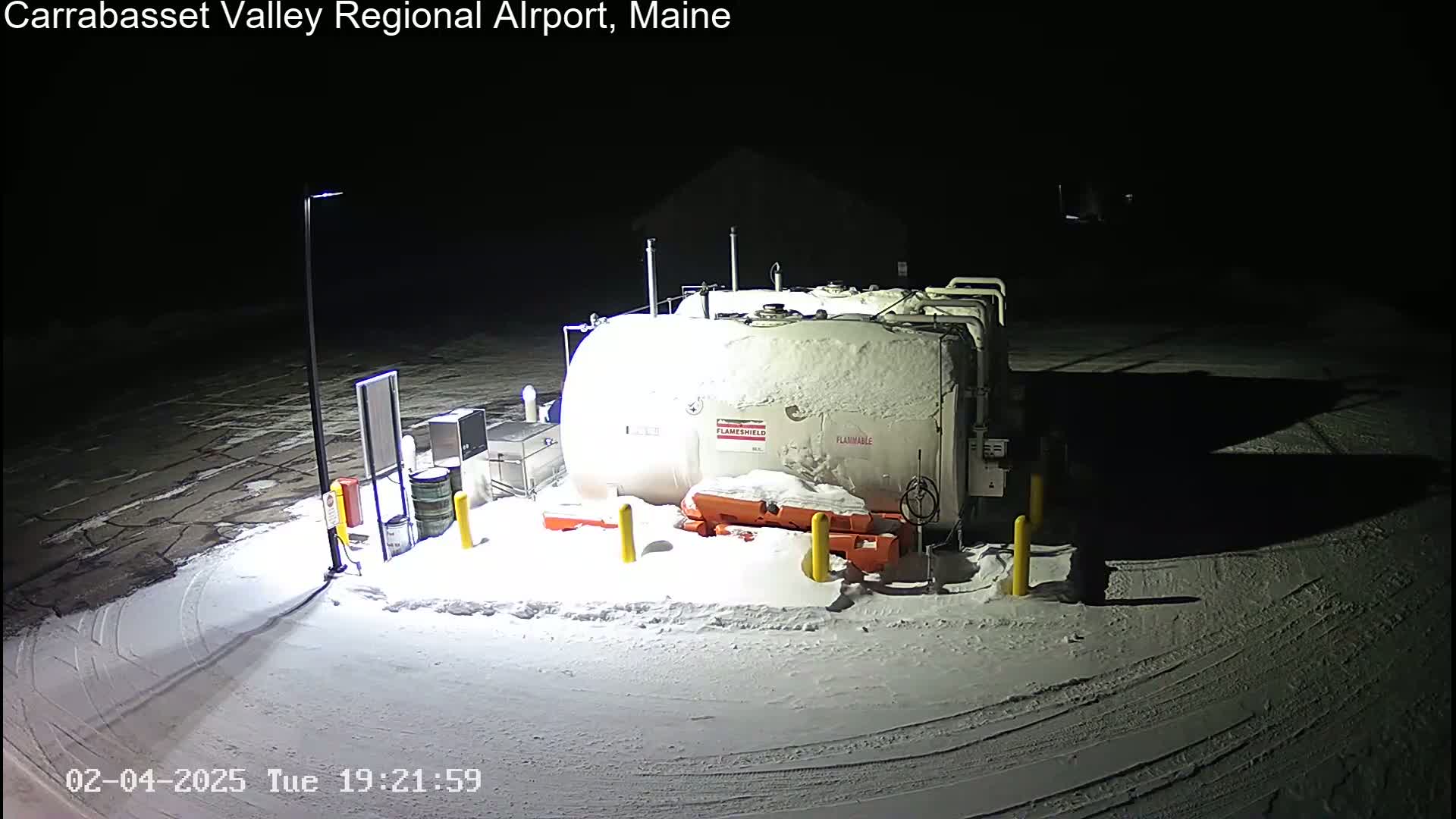 A large, snow-covered fuel tank sits in a snowy, dimly lit area at night.