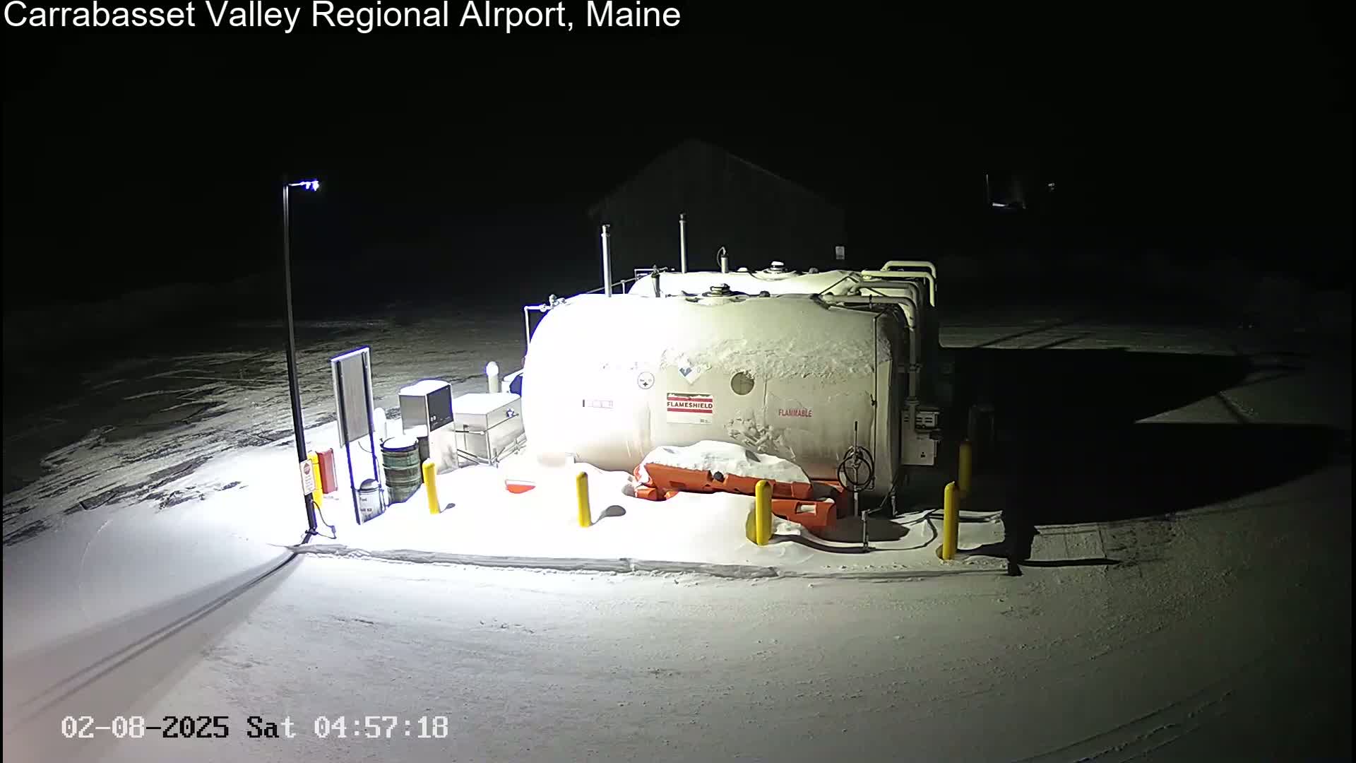 At night, under a blanket of snow, a large, snow-covered fuel tank sits in a dimly lit area.