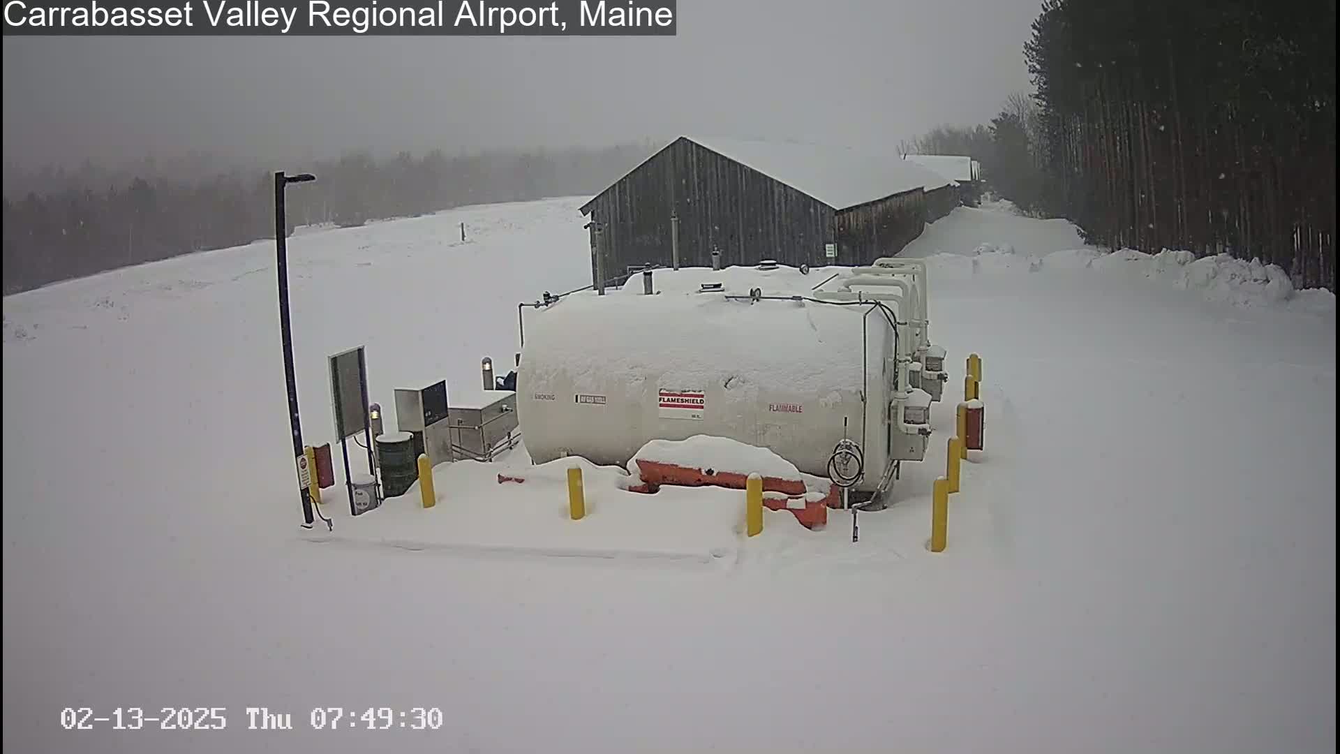 A snow-covered fuel tank and a building are visible in a snowy landscape.