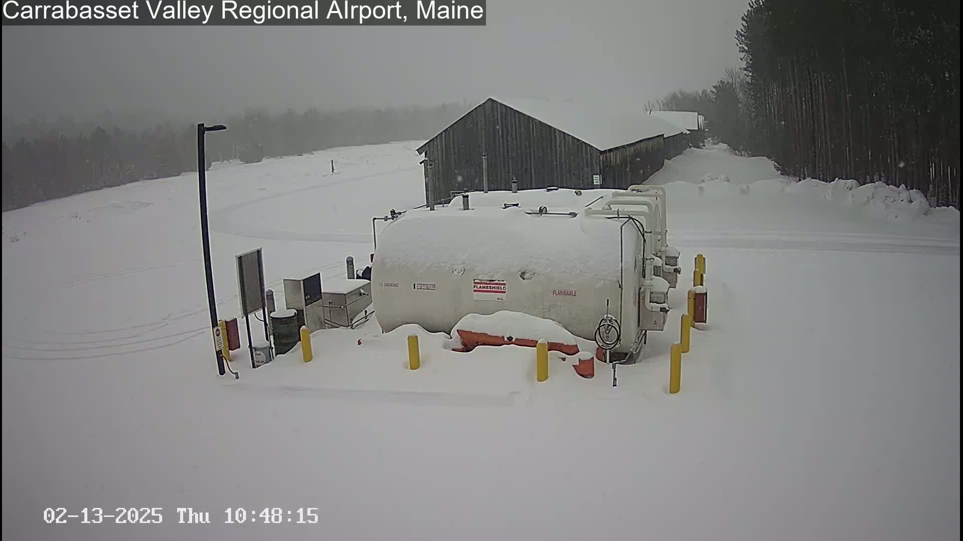 A snow-covered fuel tank and building are visible in a snowy landscape.