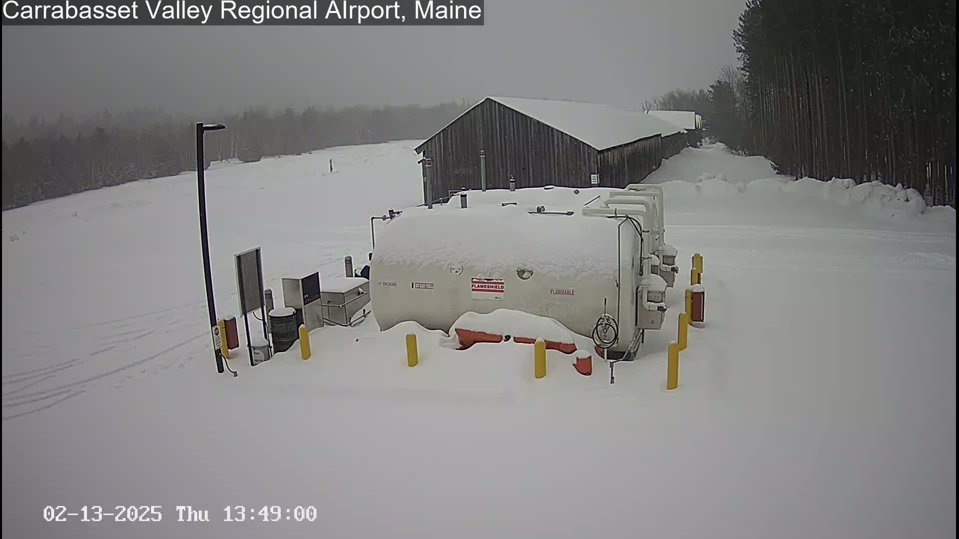 A snow-covered fuel tank and a barn are visible in a snowy landscape.