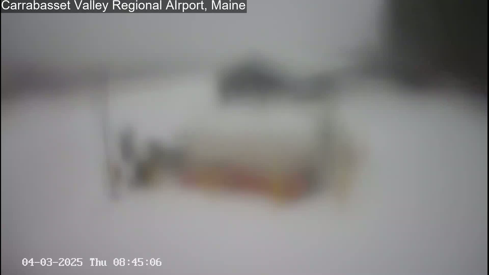 A blurry image shows an outdoor scene in snowy conditions with indistinct objects on the ground.