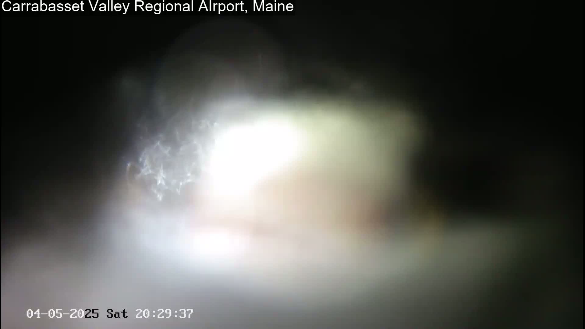 A blurry, bright light source dominates a dark, nighttime scene.