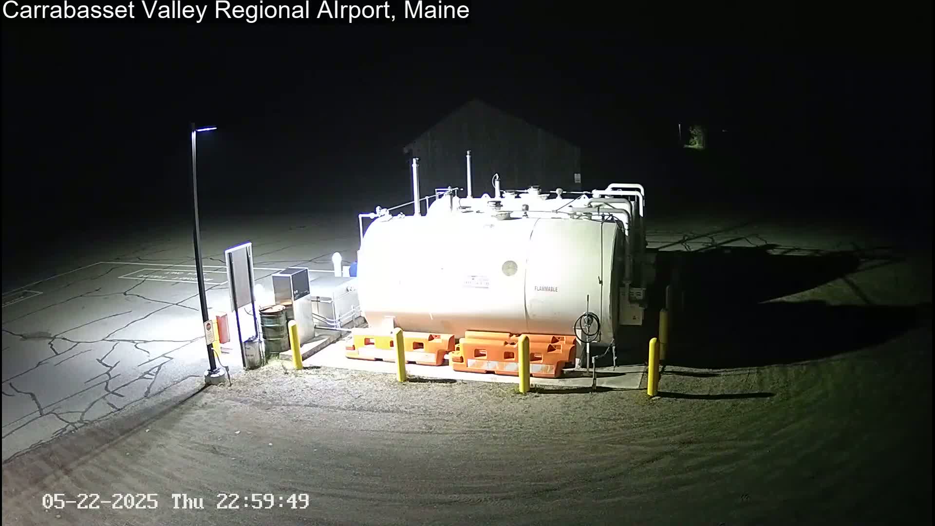 A large, white fuel tank sits in a dark, outdoor area illuminated by artificial light at night.