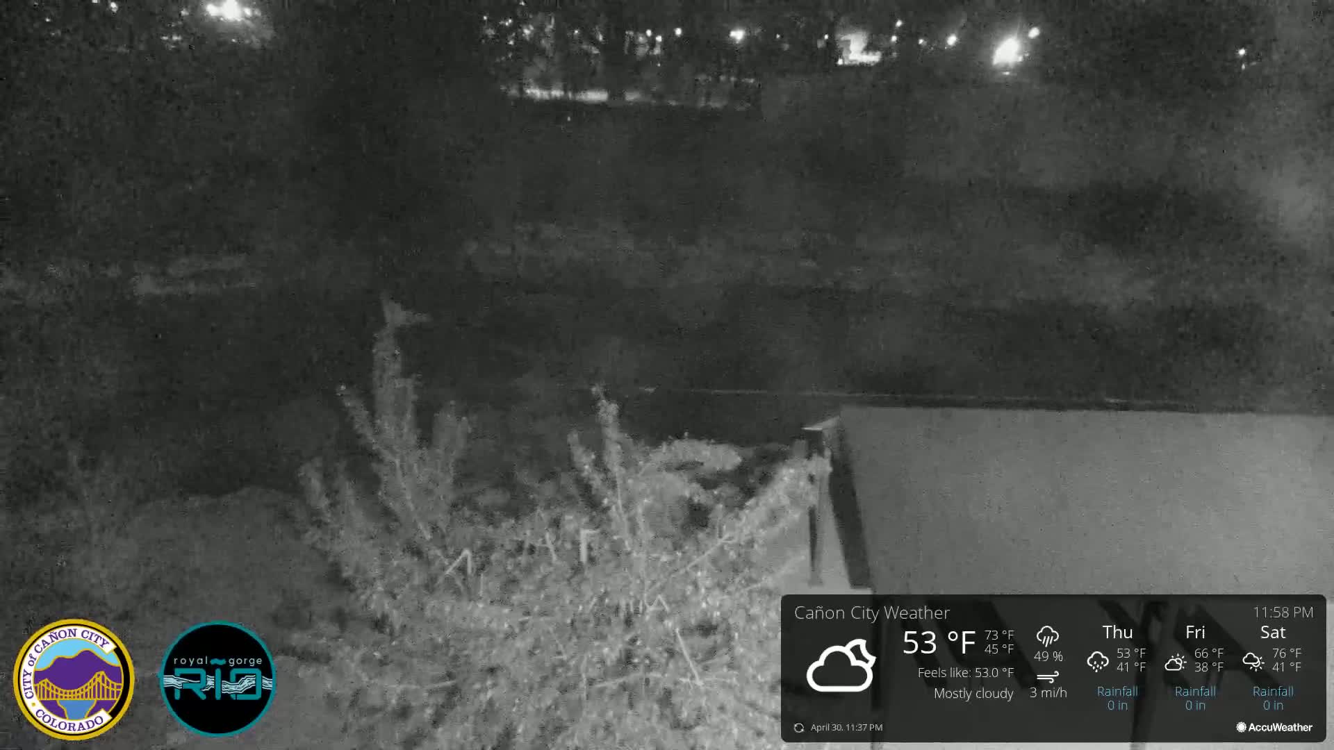 A nighttime, mostly cloudy scene shows dark vegetation near a body of water under a 53°F sky.