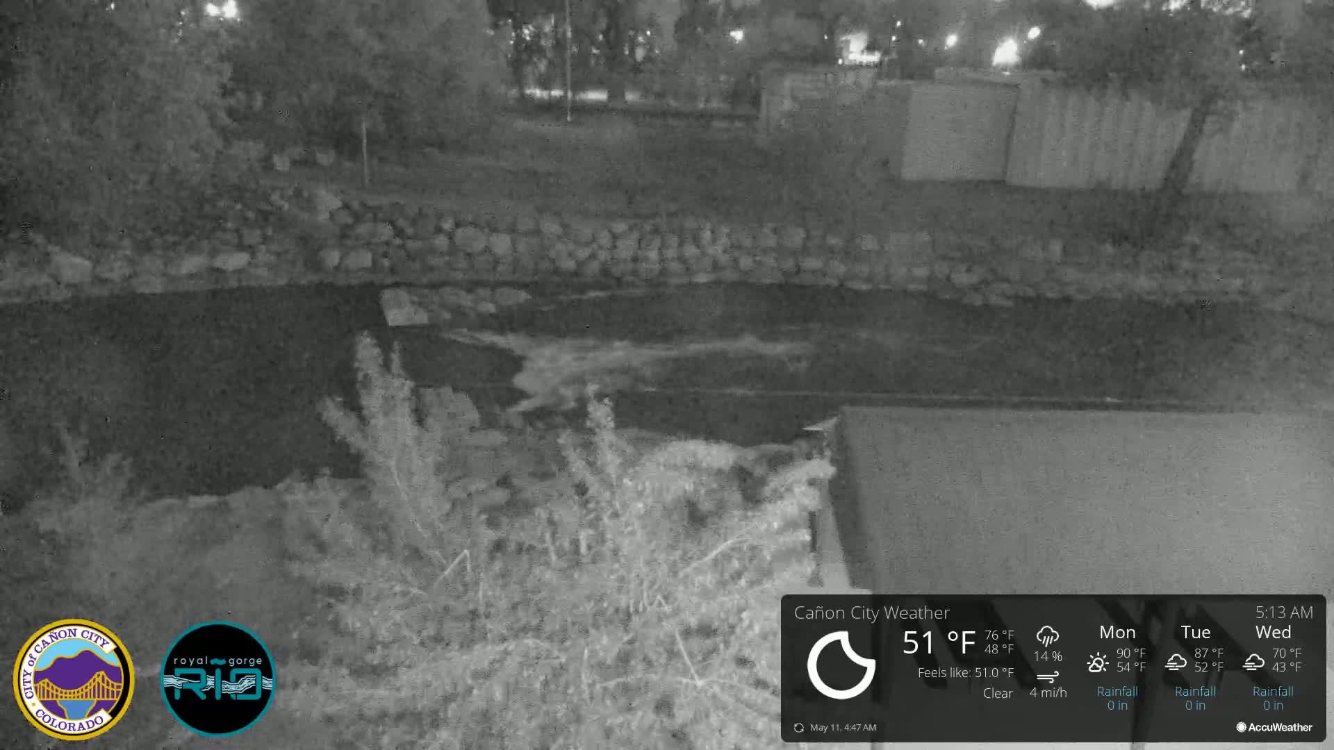 A nighttime, clear view of a body of water flowing between stone walls under a clear sky.