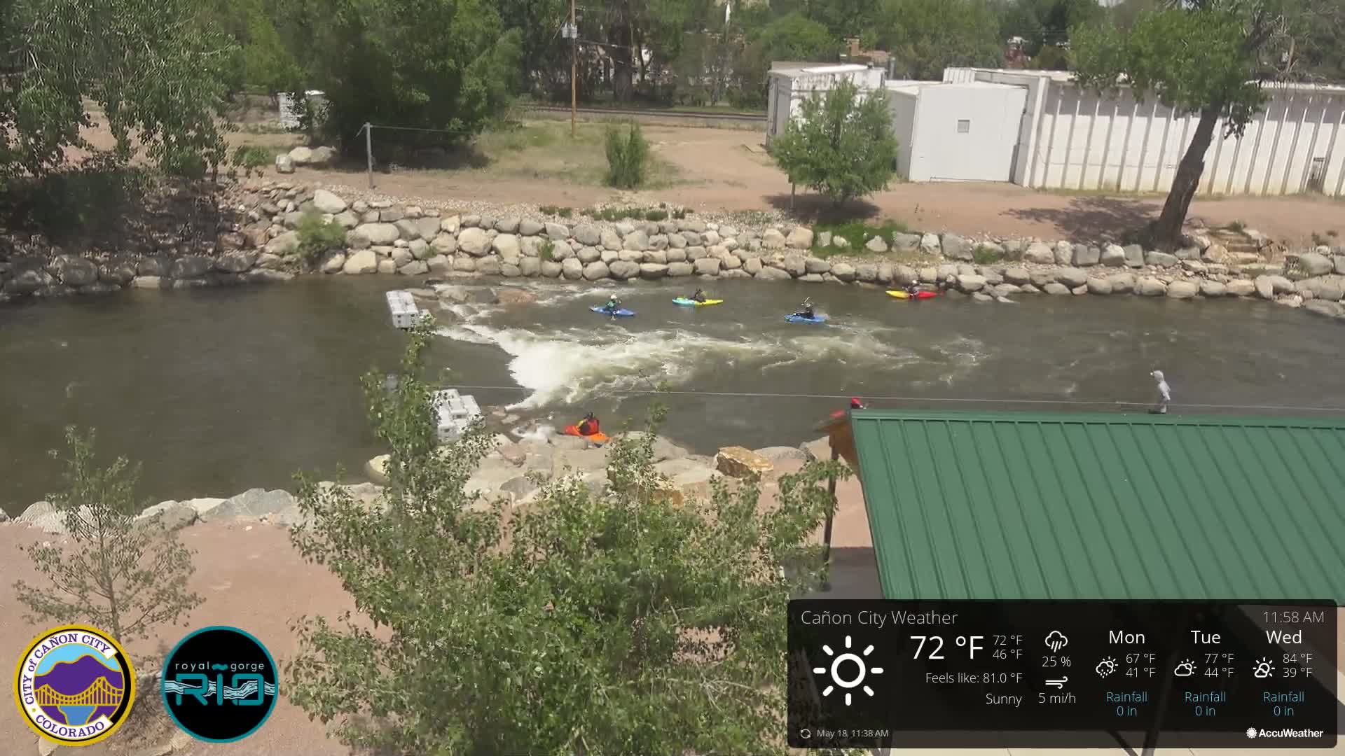 Several kayakers navigate a river under sunny skies.
