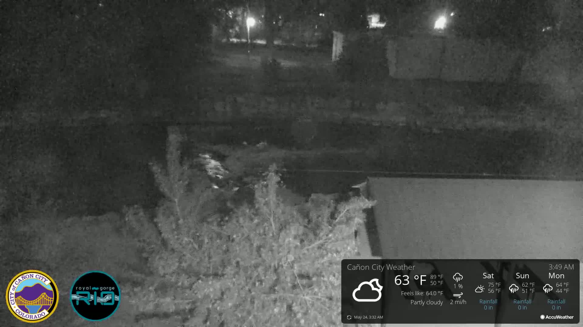 A nighttime, partly cloudy scene shows a dark body of water and vegetation under dim lighting.