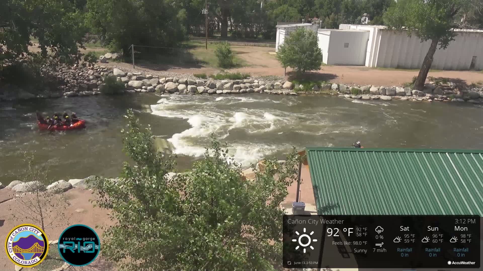 A raft carrying several people floats down a rushing river on a sunny day.